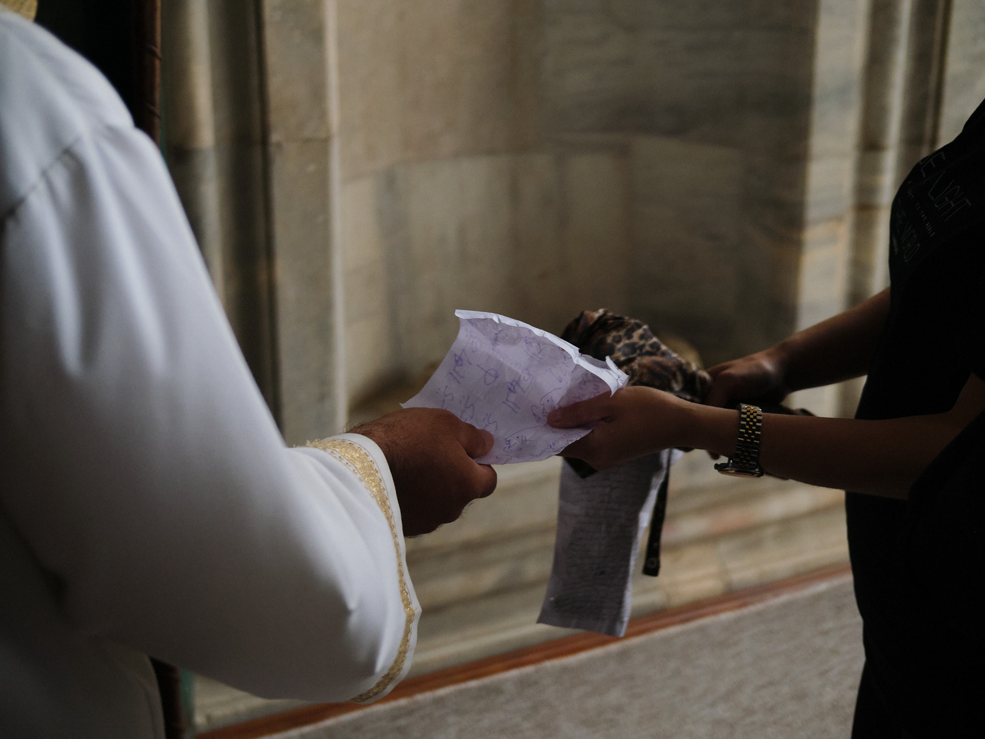 imam handing woman a note of prayers.